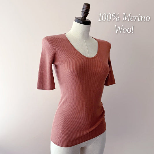 The Merino Wool Tee Top in the image is a chic and comfortable addition to any wardrobe. This top features a fitted silhouette that accentuates the figure gracefully, while the ribbed texture adds a modern twist to the classic tee design.