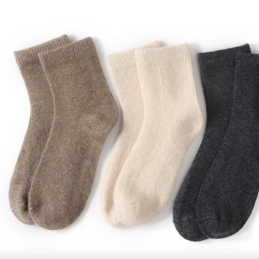 Three pairs of socks in brown, beige, and gray on a white background